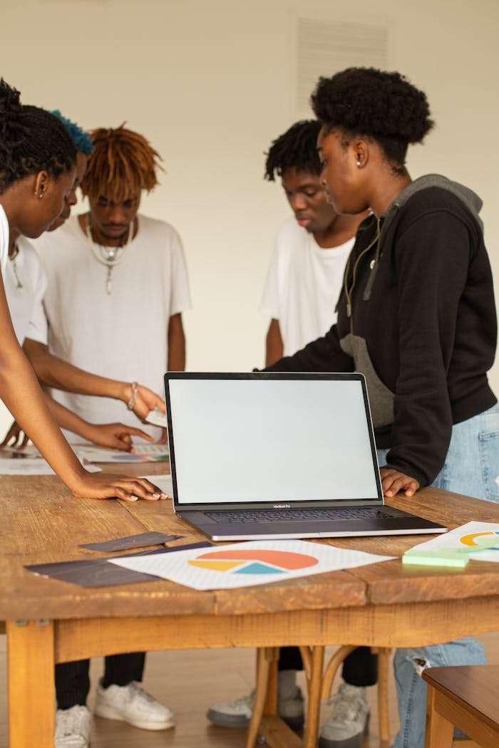 Young professionals brainstorming and planning around a laptop for creative project.